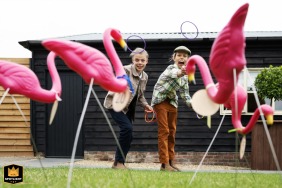 Twee jonge kinderen spelen vreugdevol een ringwerpspel tijdens een huwelijksfeest in de Milling Barn in Bluntswood Hall, Hertfordshire.